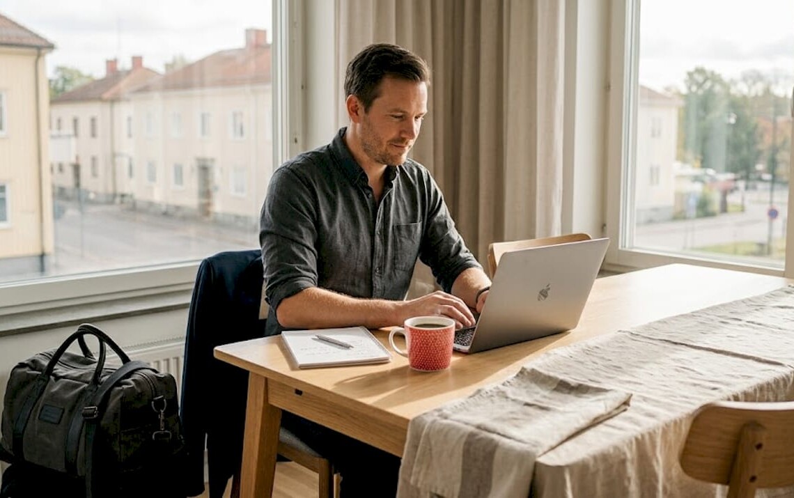 Professional working at dining table in apartment